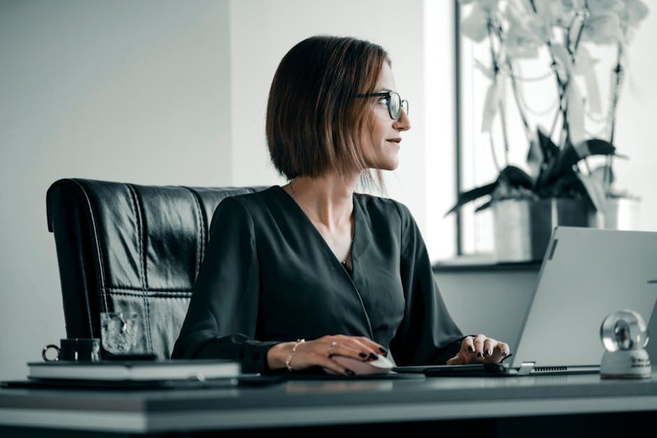 A woman sitting at her desk, deep in thought, looking overwhelmed by paperwork