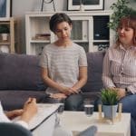 couples therapy session with two people on a couch talking to a therapist